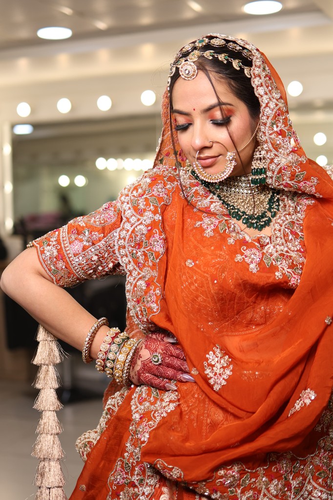 Pankhuri looking down, gold embroidery glowing on her red lehenga